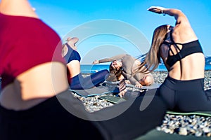 group of young females practicing yoga on the seaside