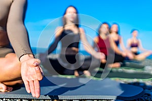 group of young females practicing yoga on the seaside