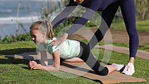 Group of young females practicing yoga on the seaside during the day. Green Grass. Gymnastic coach. Trainer