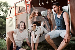 A group of young friends with a dog on a roadtrip through countryside.