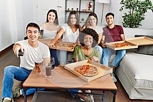 Group of young friends eating italian pizza and watching movie at home