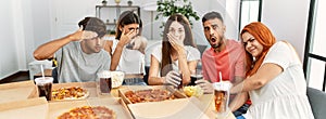 Group of young friends eating italian pizza and watching scary movie at home