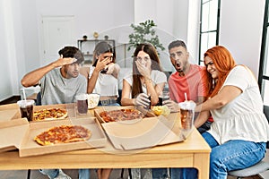 Group of young friends eating italian pizza and watching scary movie at home