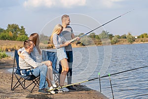 Group of young friends fishing on the pier by lakeside