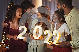 Friends holding illuminative numbers 2022 at New Years Eve midnight countdown photo