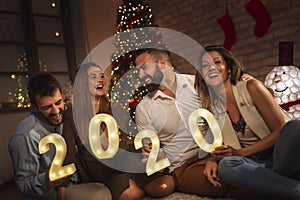 Friends celebrating New Year holding illuminative numbers 2020 photo