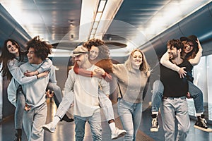 Group young friends having fun piggybacking in underground metropolitan subway - Happy trendy people enjoying nightlife