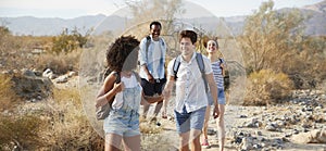 Group Of Young Friends Hiking Through Desert Countryside Together