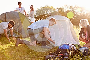 Group Of Young Friends Pitching Tents On Camping Holiday