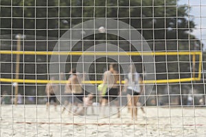 Group of young friends playing game volleyball on beach on summer day, selectiv focus. Blurred background, healthy