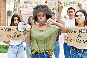 Group of young friends protesting and giving slogans at the street with angry face, negative sign showing dislike with thumbs