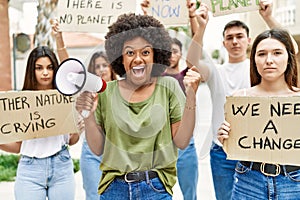 Group of young friends protesting and giving slogans at the street screaming proud, celebrating victory and success very excited