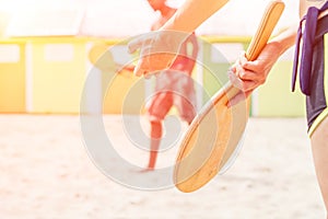 Group of young friends relaxing on sand at beach and playing with rackets - Multiracial couple having fun during summer vacation