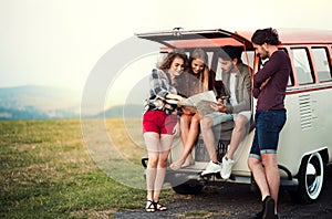 A group of young friends on a roadtrip through countryside, looking at map.