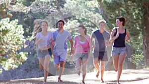 Group Of Young Friends Running Through Countryside