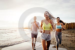 Group of young friends running and exercising on the beach