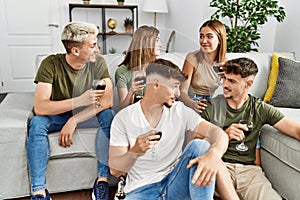 Group of young friends smiling happy drinking red wine at home