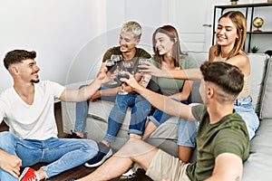Group of young friends smiling happy toasting with glass of red wine at home