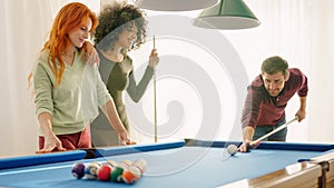 Group of young friends smiling playing billiards