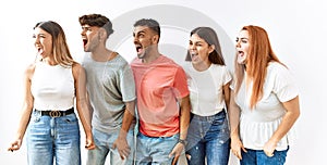 Group of young friends standing together over isolated background angry and mad screaming frustrated and furious, shouting with