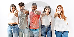 Group of young friends standing together over isolated background pointing displeased and frustrated to the camera, angry and