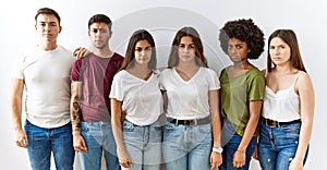 Group of young friends standing together over isolated background skeptic and nervous, frowning upset because of problem
