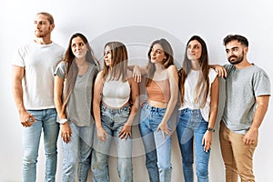 Group of young friends standing together over isolated background smiling looking to the side and staring away thinking