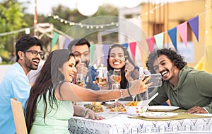 group of young friends taking selfie at evening new year party on terrace - concept of social media sharing, birthday