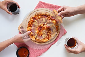 Group of young friends tasting pizza and drinking soft drink on