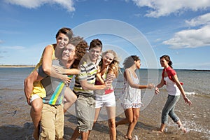 Group Of Young Friends Walking Along Shoreline