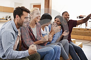 Group Of Young Friends Watching Sports On Television And Cheering