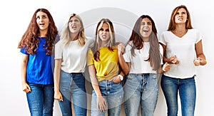 Group of young girl friends standing together over isolated background angry and mad screaming frustrated and furious, shouting
