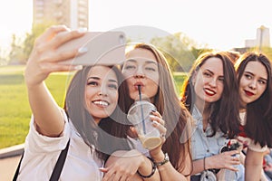 Group of young happy carefree girls friends making selfie on summer city street, sunset time background