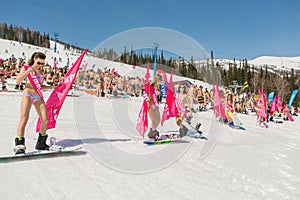 Group of young happy pretty women on a snowboard in colorful bikini with flags.