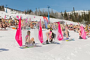 Group of young happy pretty women on a snowboard in colorful bikini with flags.