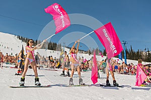 Group of young happy pretty women on a snowboard in colorful bikini with flags.