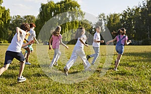 Group of a young happy smiling school kids friends running in the summer park.