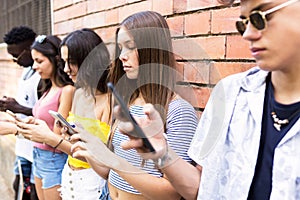 Group of young hipster friends using smart phone in an urban area.
