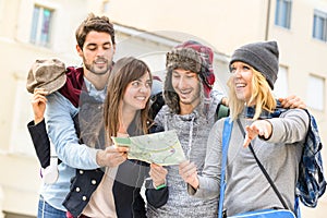 Group of young hipster tourists friends cheering with city map