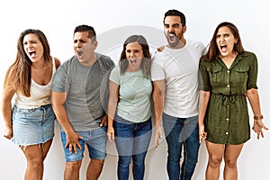 Group of young hispanic friends standing together over isolated background angry and mad screaming frustrated and furious,