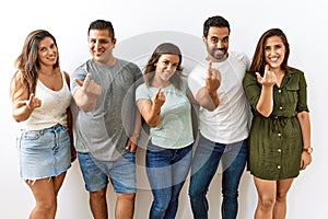 Group of young hispanic friends standing together over isolated background beckoning come here gesture with hand inviting