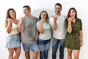 Group of young hispanic friends standing together over isolated background smiling with happy face looking and pointing to the
