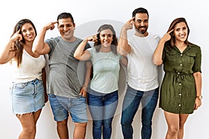 Group of young hispanic friends standing together over isolated background smiling pointing to head with one finger, great idea or