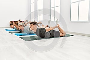 Group of young hispanic people smiling happy stretching at sport center