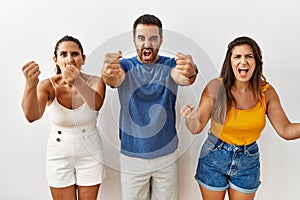 Group of young hispanic people standing over isolated background angry and mad raising fists frustrated and furious while shouting