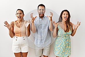 Group of young hispanic people standing over isolated background celebrating mad and crazy for success with arms raised and closed