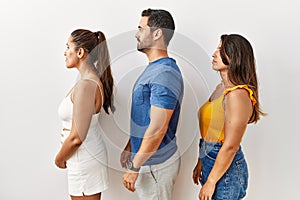 Group of young hispanic people standing over isolated background looking to side, relax profile pose with natural face and