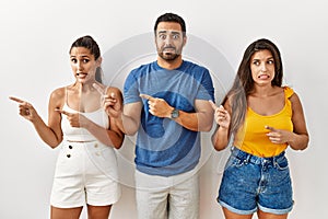 Group of young hispanic people standing over isolated background pointing aside worried and nervous with both hands, concerned and