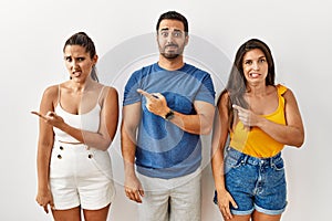 Group of young hispanic people standing over isolated background pointing aside worried and nervous with forefinger, concerned and