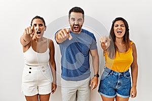 Group of young hispanic people standing over isolated background pointing displeased and frustrated to the camera, angry and